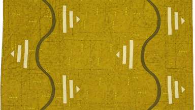 Detail of mustard colored quilt with black lines and white triangles
