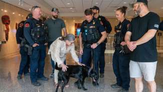 Several officers surround Ms. Langley while she bends over to pet a black lab member of the K9 unit.
